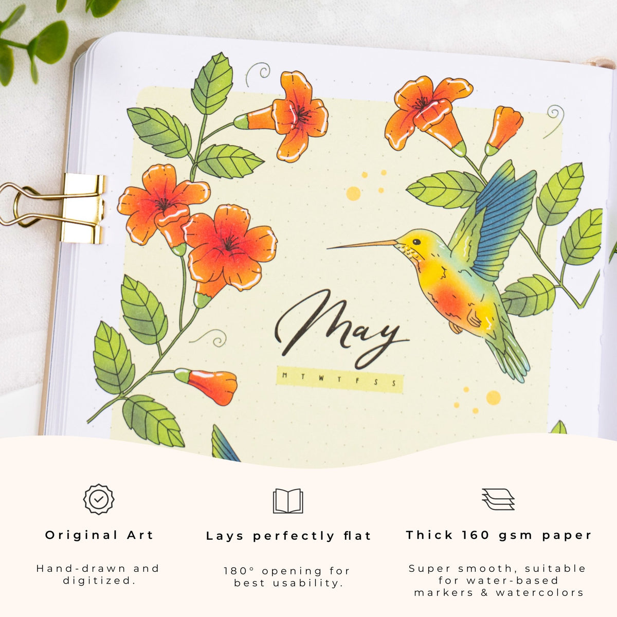 Gros plan d'une page de carnet présentant une illustration colorée de fleurs et de colibri, le mois « mai », et les points forts du produit : art original, design à plat, et papier super lisse épais de 160 g/m².