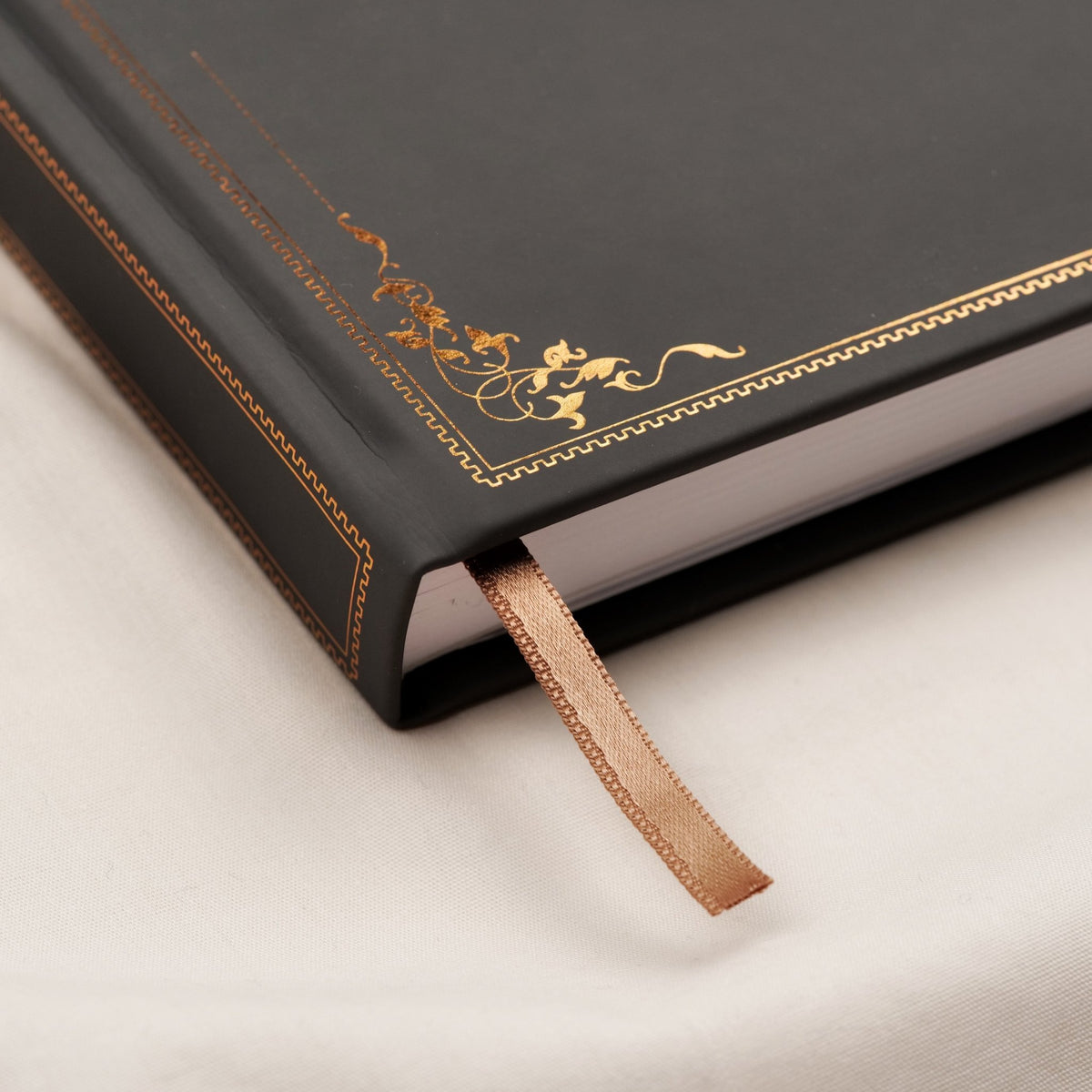 Showing the embossed gold copper detail and satin brown bookmark of the deep gray premade Travel Notebook.