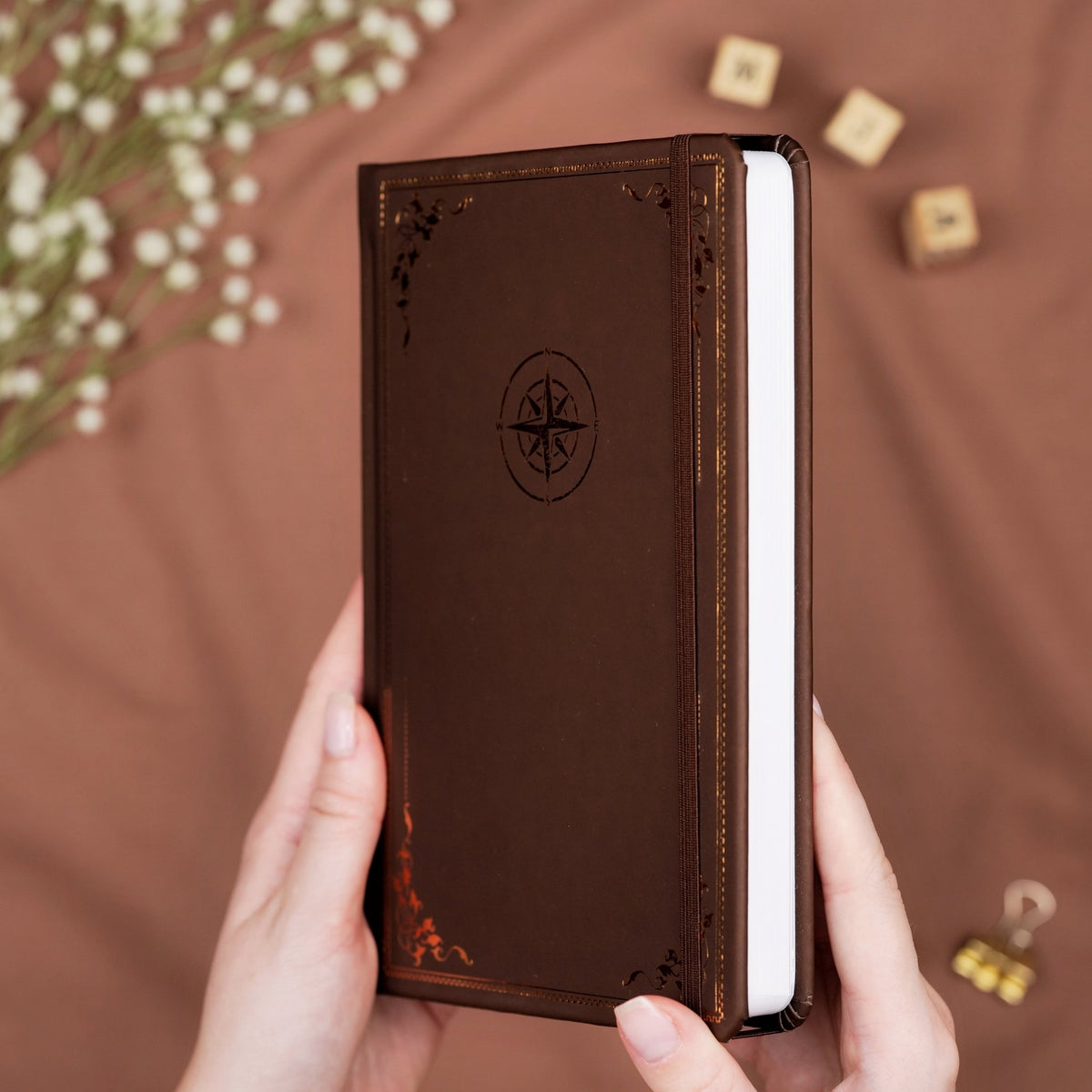 Brown premade dotted bullet style travel journal made of Italian vegan leather with an embossed gold copper compass design.