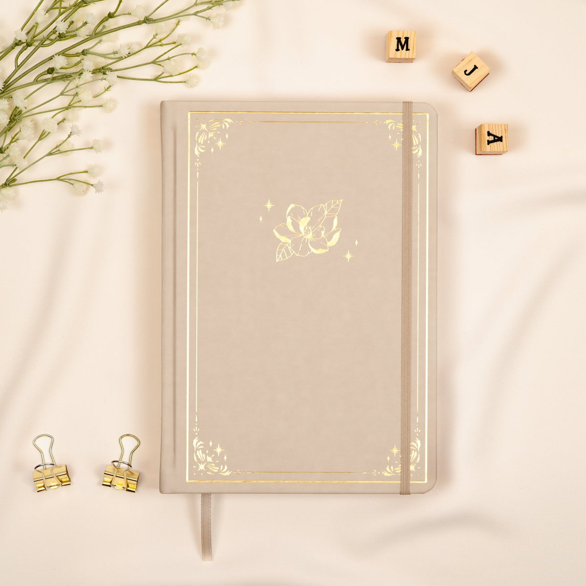 Oat beige premade dotted bullet style journal made of Italian vegan leather with an embossed gold magnolia design.