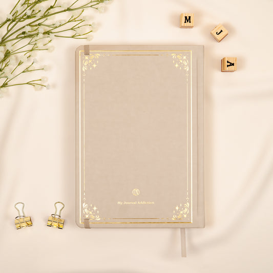 Vegan leather back cover of the beige neutral oat premade bullet style journal with embossed gold logo detail.