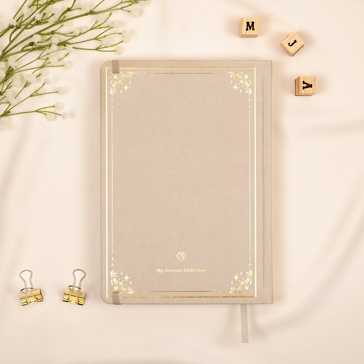 Vegan leather back cover of the beige neutral oat premade bullet style journal with embossed gold logo detail.