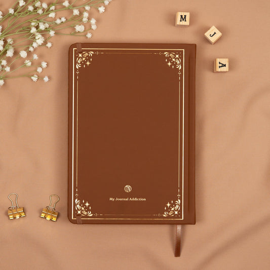 Vegan leather back cover of the brown cinnamon premade bullet style journal with embossed gold logo detail.
