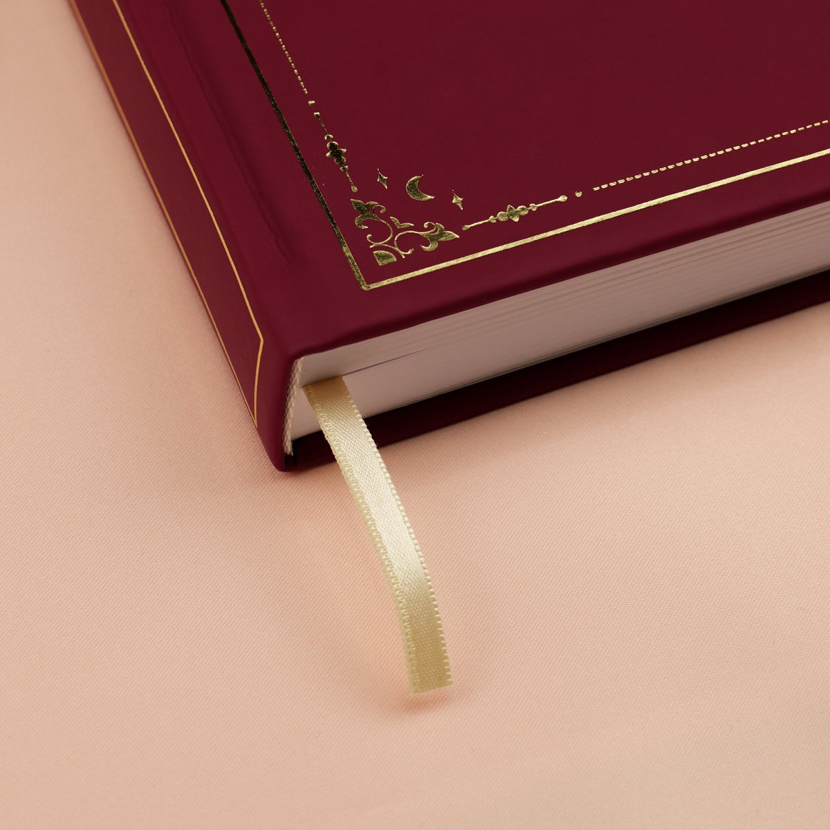 Showing the embossed gold detail and satin beige bookmark of the red Forbidden Fruit premade bullet style journal.