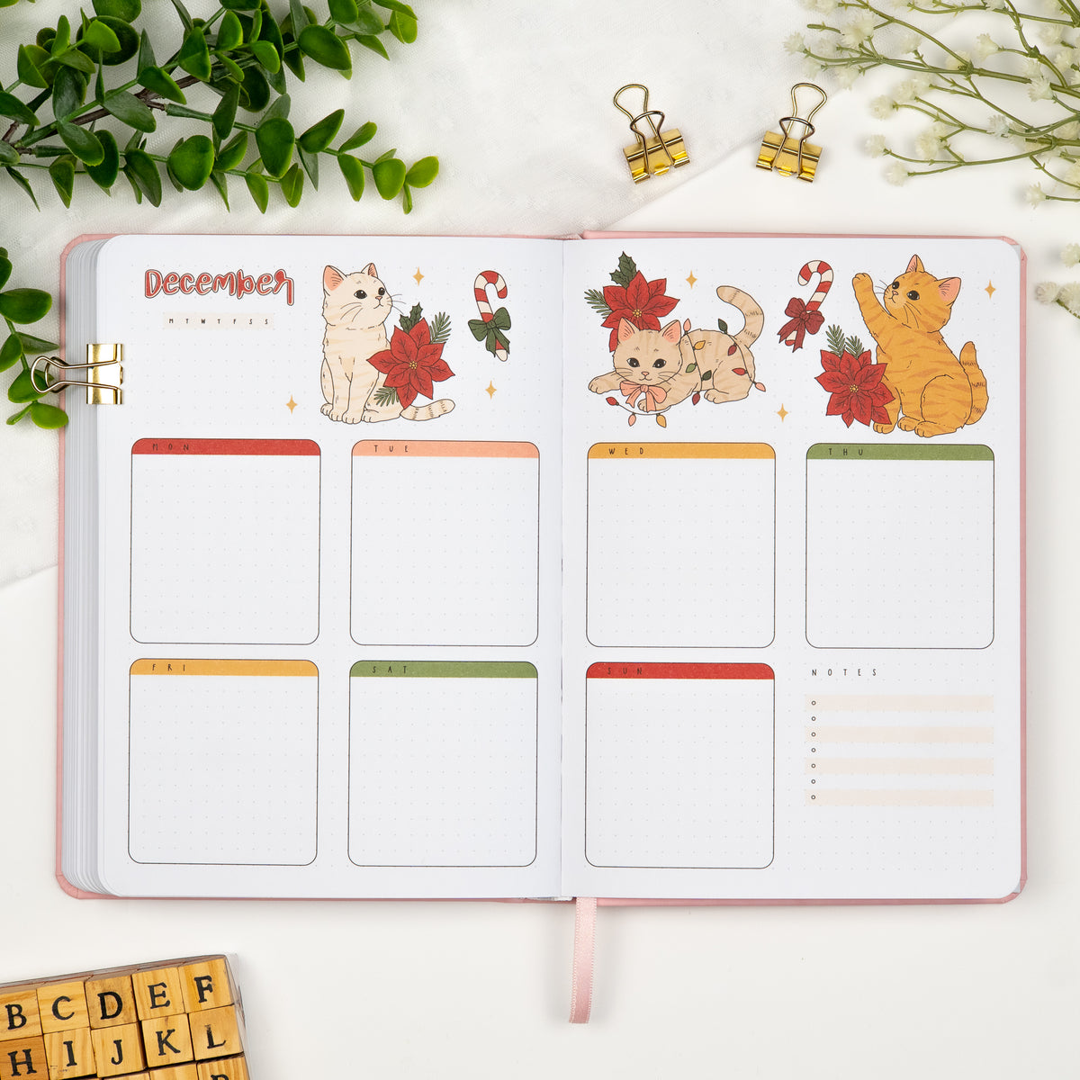 First monthly weekly layout of a premade journal, with calligraphy December title, calendar, days and colored illustrations of cats with christmas doodles.